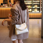 Person holding a white handbag in an indoor setting