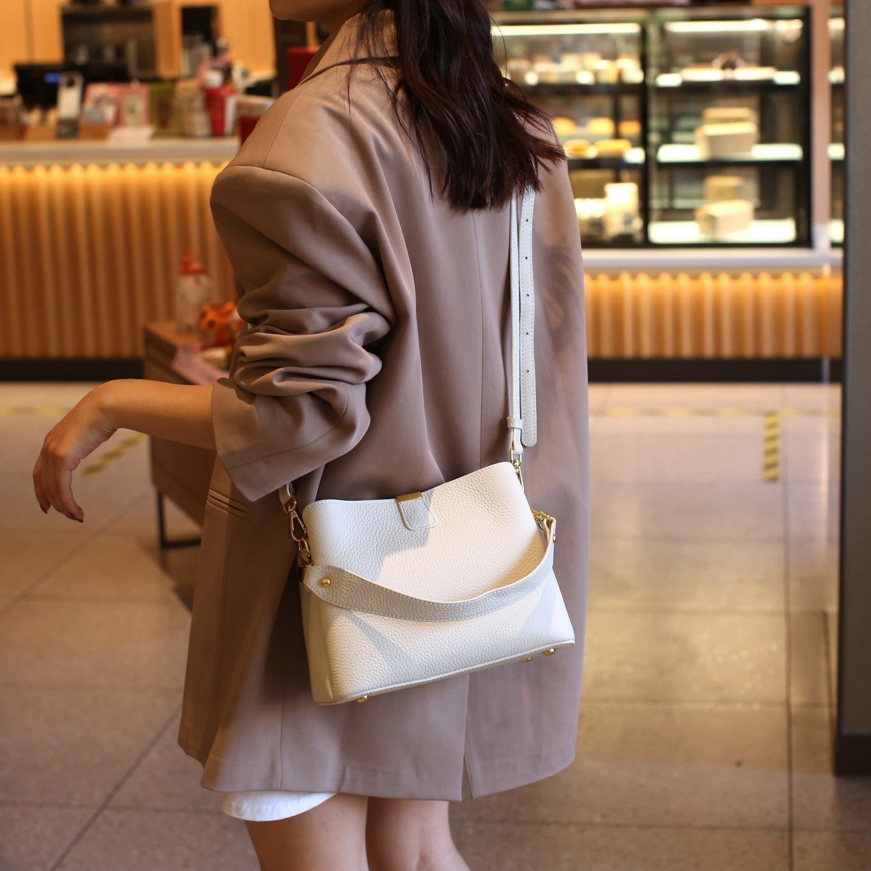 Person holding a white handbag in an indoor setting