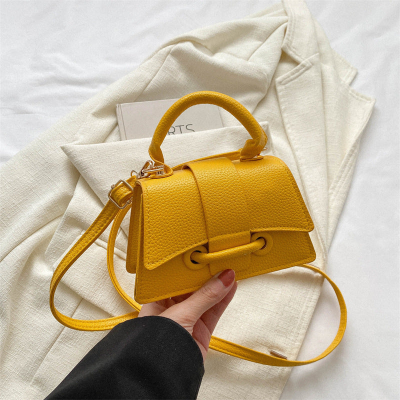 Yellow handbag held by a hand on a white background