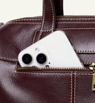 Smartphone with a white case peeking out from a brown leather bag