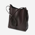 Brown leather handbag with a shoulder strap on a light gray background
