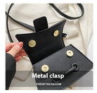 Black leather pouch with metal clasps held by a hand on a light background