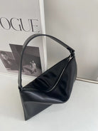 Black handbag on a light surface with 'Vogue' magazine in the background