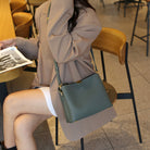 Person sitting at a cafe table with a green handbag