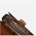 Close-up of a brown leather handbag with gold zipper and clasp on a white background