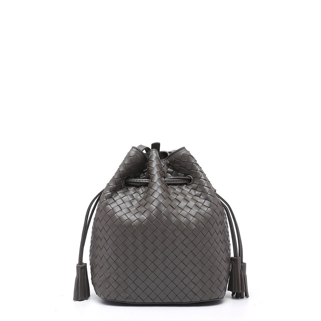 Black woven bucket bag with tassels on a white background