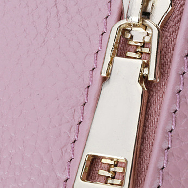 Close-up of a pink textured surface with a gold zipper and pull.