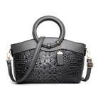 Black handbag with crocodile texture and round handle on a white background