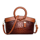 Brown leather handbag with crocodile texture on a white background
