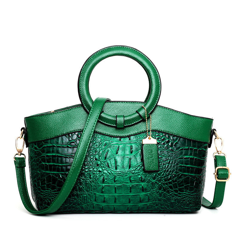 Green handbag with crocodile texture on a white background