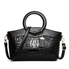Black handbag with crocodile texture and round handles on a white background