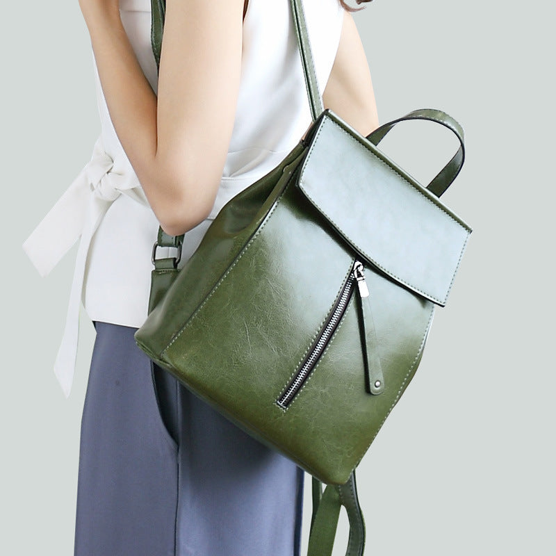 Green backpack worn by a person on a light gray background