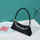 Black handbag on a white surface with a teal background