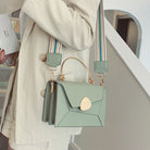 Light green handbag with gold accents held by a person wearing a beige coat.