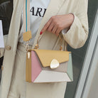 Person holding a colorful handbag with a neutral background