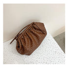 Brown woven handbag on a speckled white surface with a neutral background