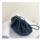 Blue woven handbag on an open book with a light background