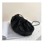 Black woven handbag on an open book with a light background