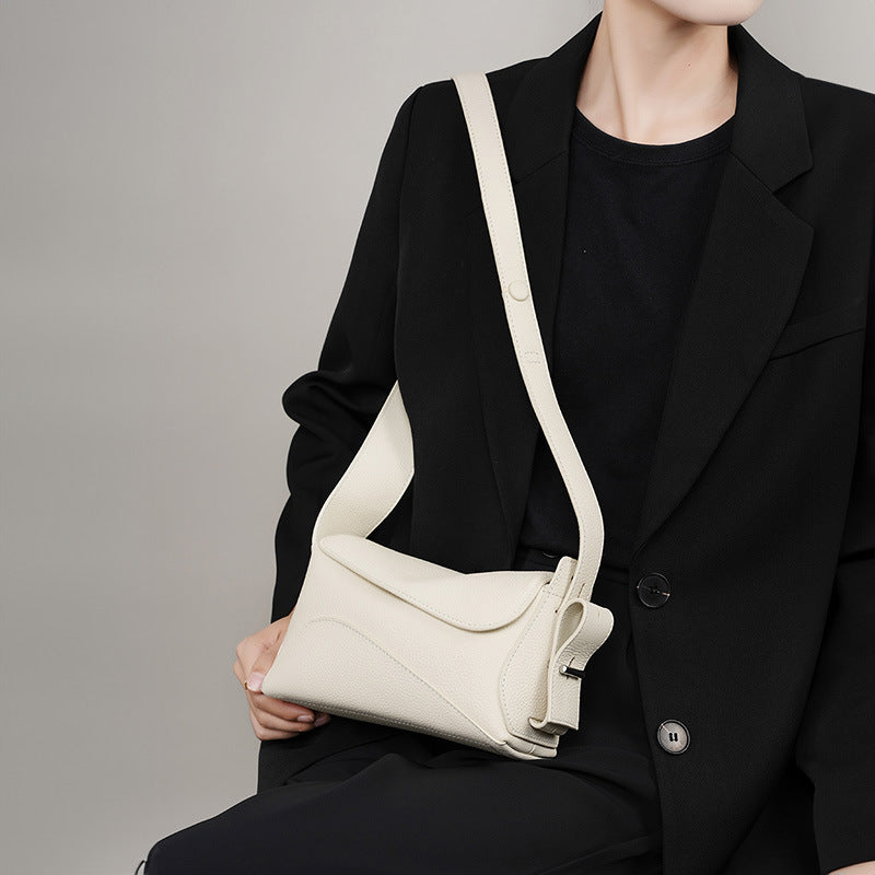 Person wearing a black outfit with a white shoulder bag on a gray background