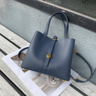 Blue handbag on a wooden surface with a magazine underneath