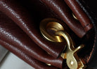 Close-up of a brown leather bag with a gold clasp on a white background