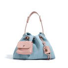 Light blue Denim drawstring bag with pink leather pouch and strap on a white background
