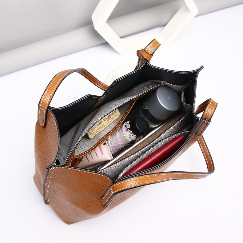 Brown leather handbag with items inside on a white background