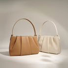 Two handbags, one brown and one beige, on a neutral background
