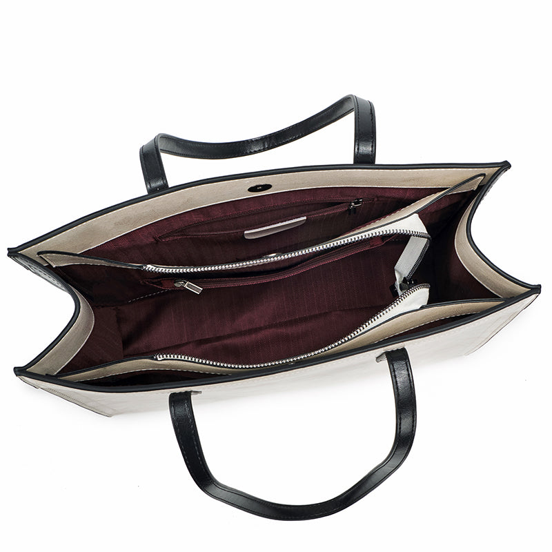 Open handbag showing interior with a white exterior and black handles on a white background