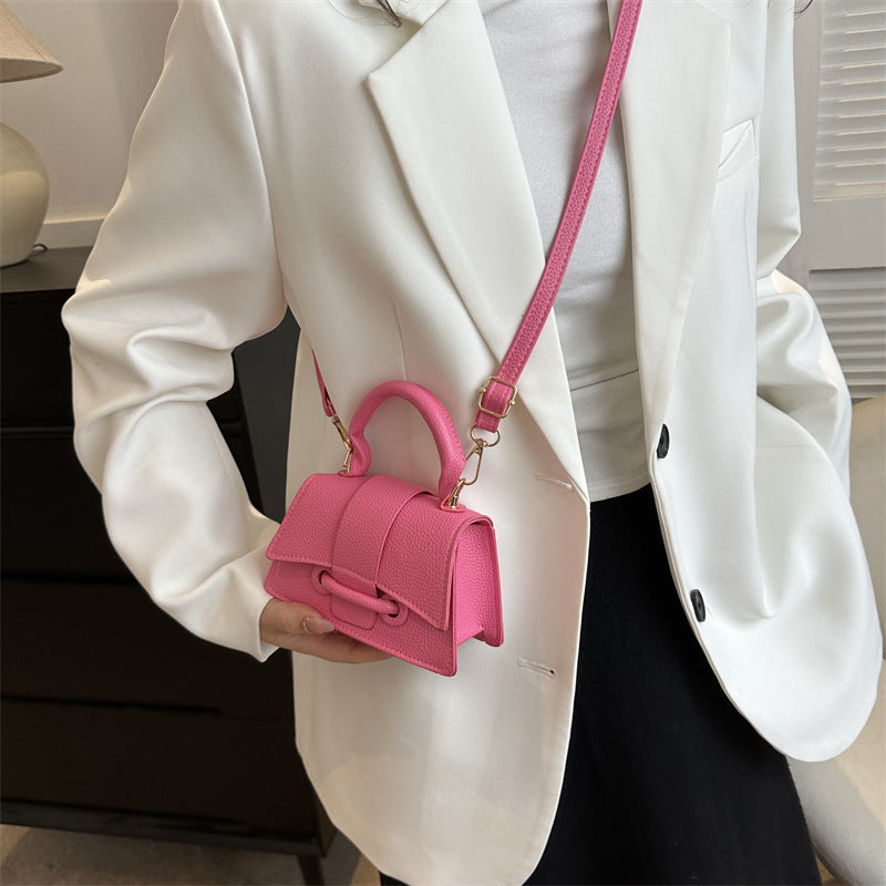 Person holding a pink handbag with a white blazer