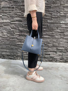 Person holding a blue handbag against a stone wall.