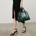 Person holding a green handbag against a neutral background