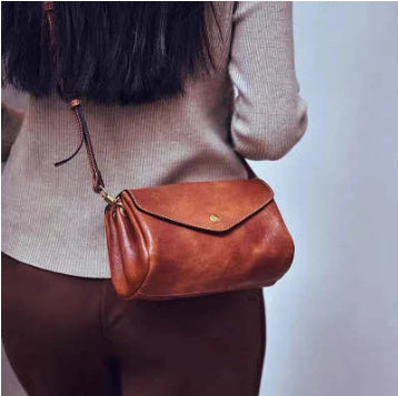 Brown leather handbag worn over shoulder against a neutral background