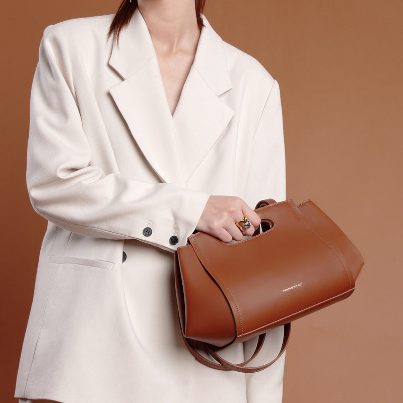 Person holding a brown handbag against a brown background