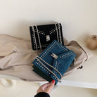 Black and blue handbags with studded details on a beige surface.