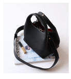 Black handbag on a magazine with a white background
