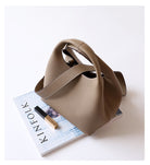 Beige handbag on a magazine with a white background