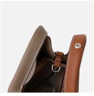 Close-up of a brown leather bag with a strap on a white background