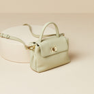Light green handbag with gold accents on a beige background