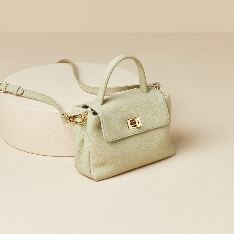 Light green handbag with gold accents on a beige background