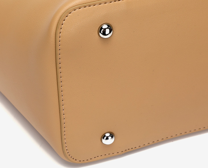 Close-up of a tan leather bag with silver studs on a white background