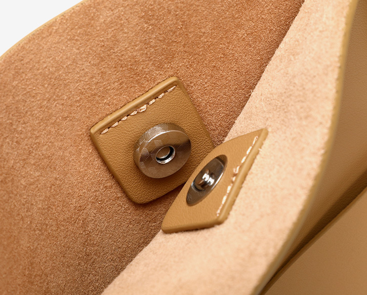 Close-up of a brown leather button on a beige fabric surface