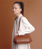 Woman holding a brown handbag against a brown background