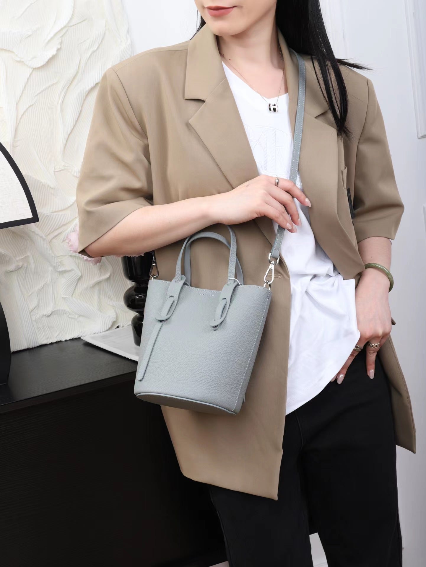 Person holding a light blue handbag against a neutral background