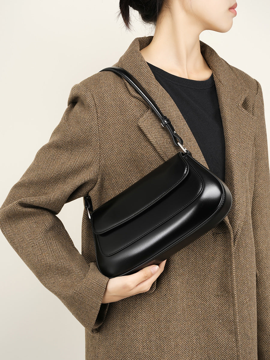 Person holding a black handbag against a neutral background