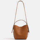 Brown leather handbag with a strap on a light beige background