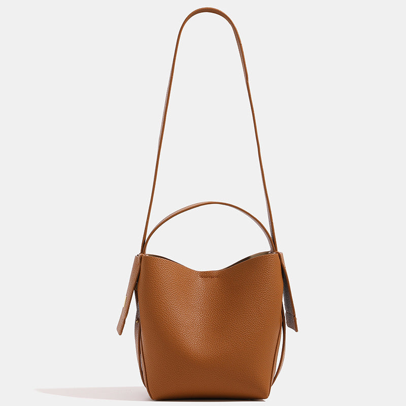 Brown leather handbag with a strap on a light beige background