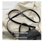 Black leather handbag with comfort shoulder strap on a white fabric background