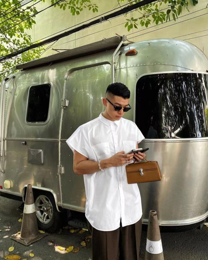 Man using a smartphone in front of a silver Airstream trailer
