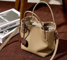 Beige handbag on a brown surface with books in the background